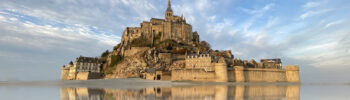 Beautiful Mont Saint Michel with water reflection and clouds on blue sky, France