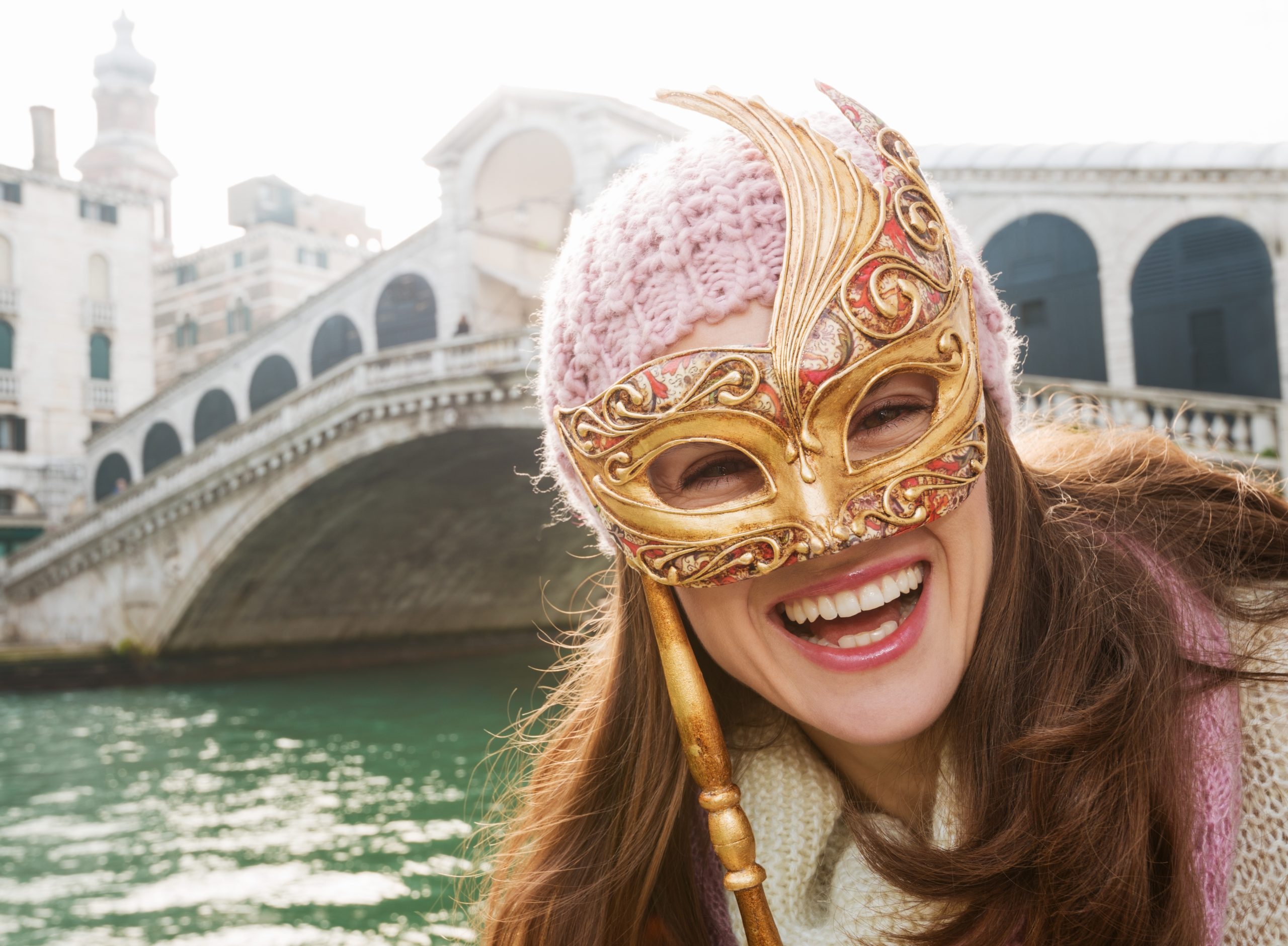 Happy woman holding Venice Mask in the front of Rialto Bridge