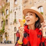 Young hipster traveler eating ice-cream in old Italian town